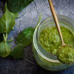Barattolo di pesto con etichetta evidenziata, simboli di avvertimento sulla salute.
