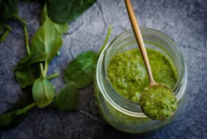 Barattolo di pesto con etichetta evidenziata, simboli di avvertimento sulla salute.